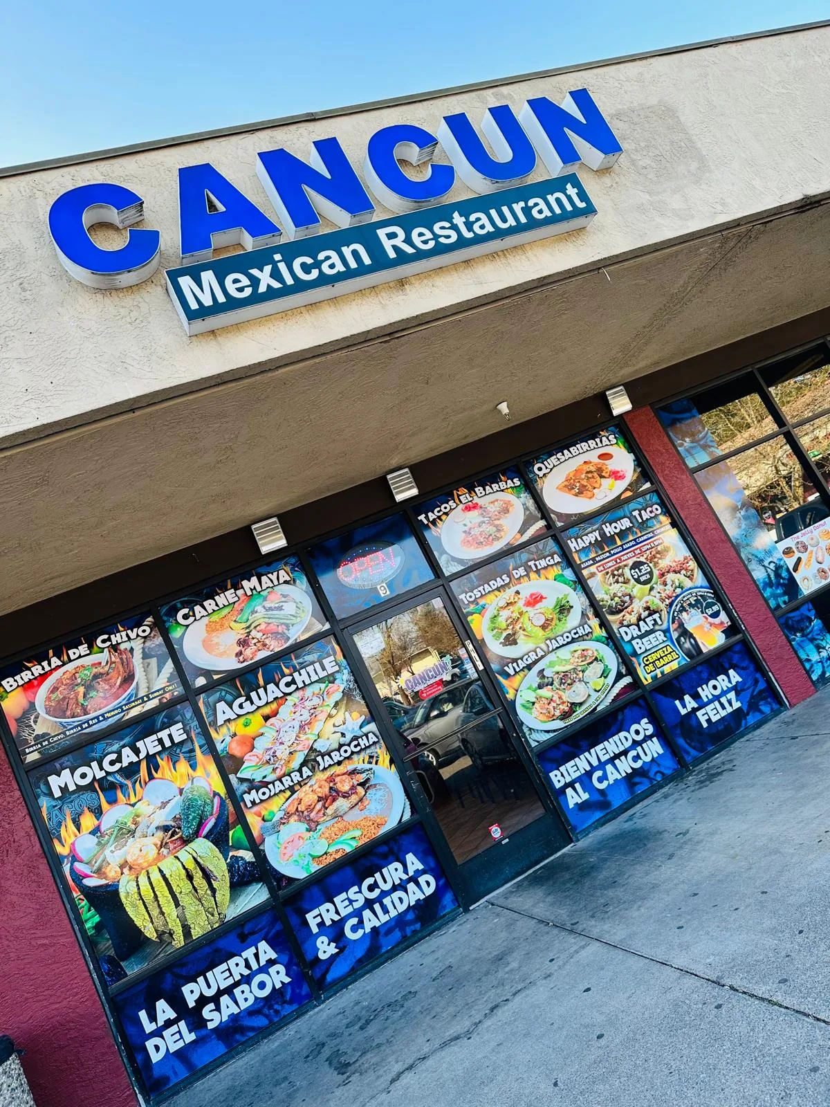 Cancun Mexican Restaurant storefront with its blue sign and window posters of the menu