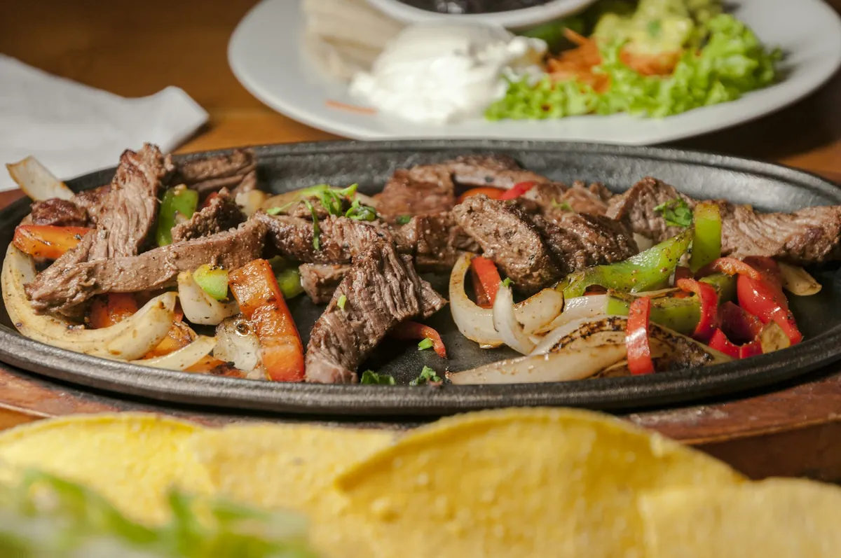 Beef fajitas with peppers and onions on a hot skillet